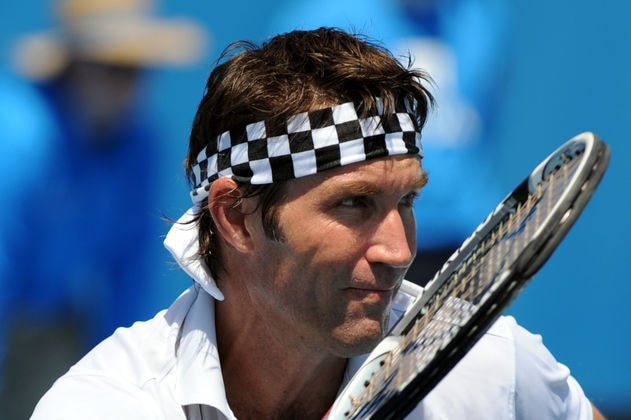 A close-up photograph of tennis player Pat Cash wearing a chequer headband and with a tennis racquet.