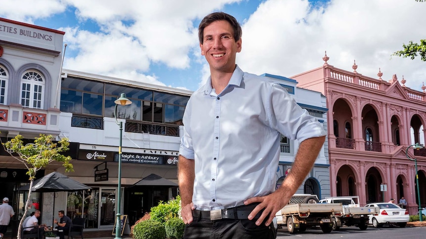 A man stands in front of heritage buildings in a street.