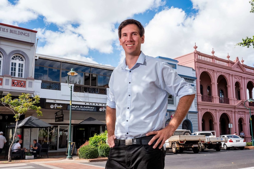 A man stands in front of heritage buildings in a street.