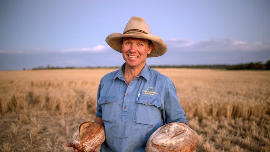 Grain grower Simon Doolin standing in the field which supplied the wheat for the bread he is holding.