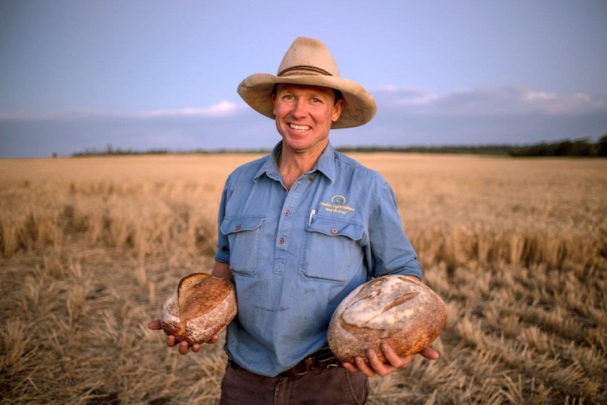Grain grower Simon Doolin standing in the field which supplied the wheat for the bread he is holding.