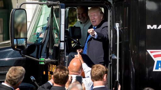 US President Donald Trump points to people while sitting inside an 18-wheeler truck at the White House.