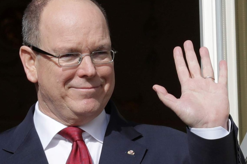 A bald man on a balcony waves while a small boy stands beside him.