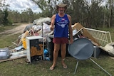 Jack Lumby gives a thumbs up in front of a pile of his ruined possessions