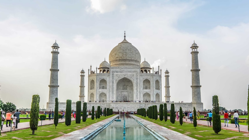 A front on view of the Taj Mahal with tourists walking towards it