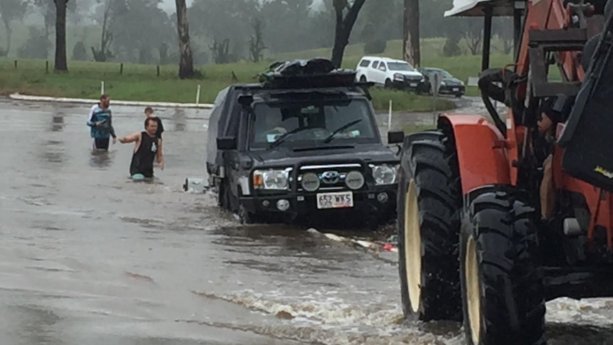 A tractor towing a car from floodwater