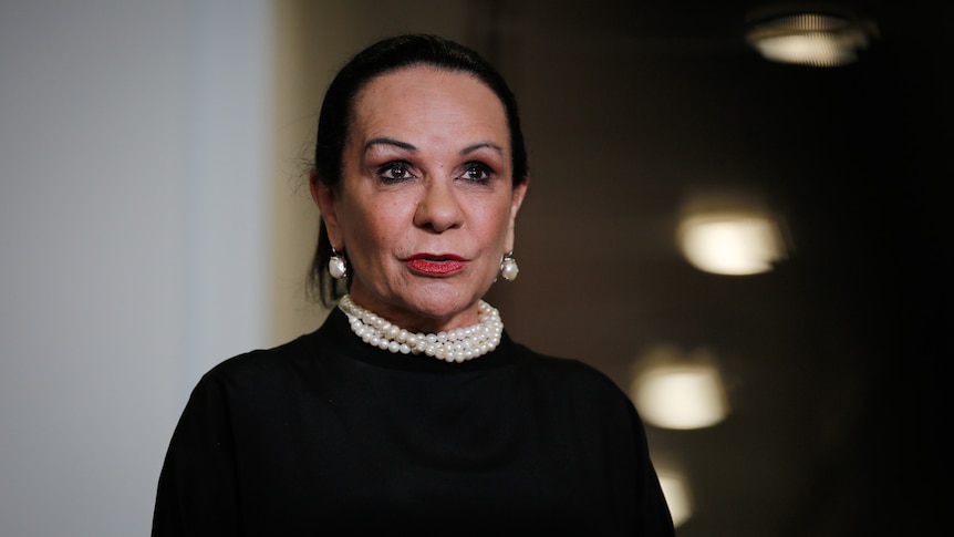 Linda Burney wearing black with pearls on the national day of mourning, with the background blurred