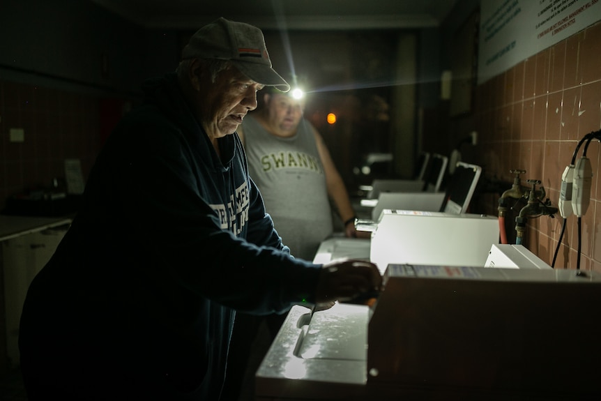 Men with head torches work on a washing machine.