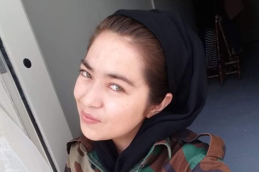 A woman wearing a black headscarf and a camouflage uniform in a selfie