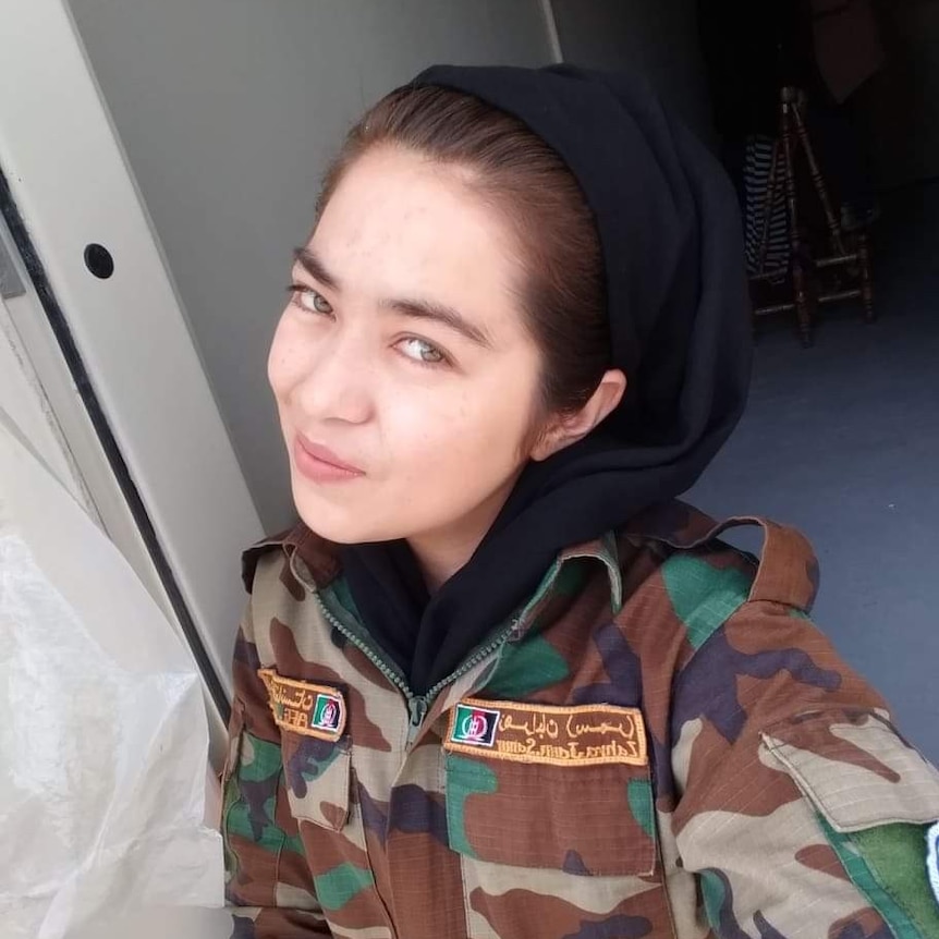 A woman wearing a black headscarf and a camouflage uniform in a selfie