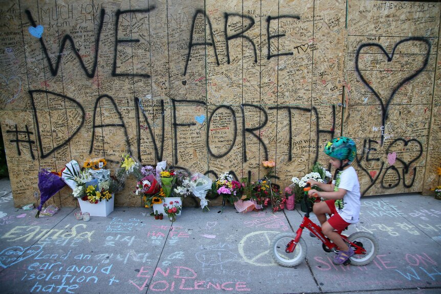 Torionto boy rides tryke past Danforth shooting memorial