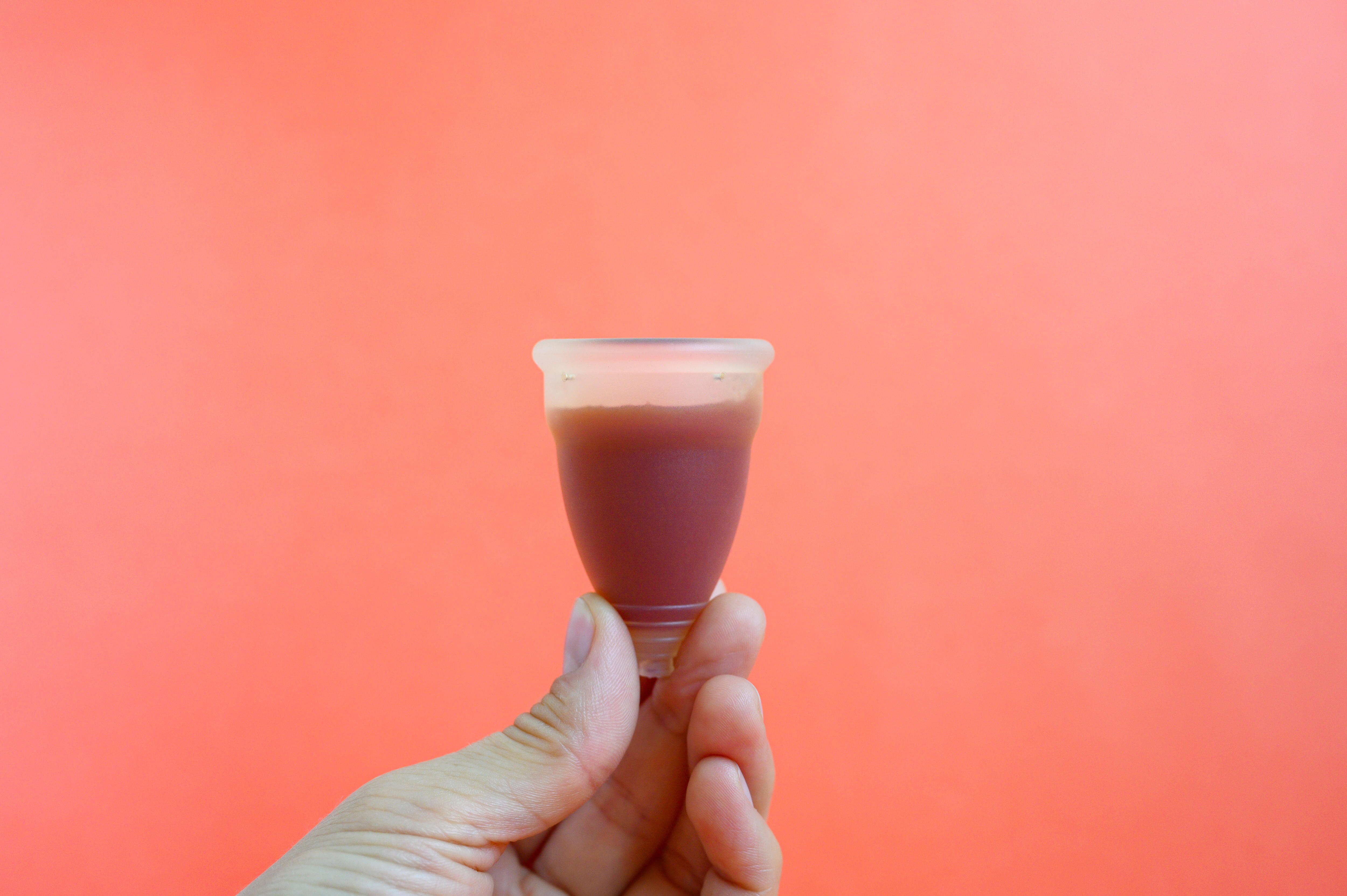 close up of person holding period cup with blood in it