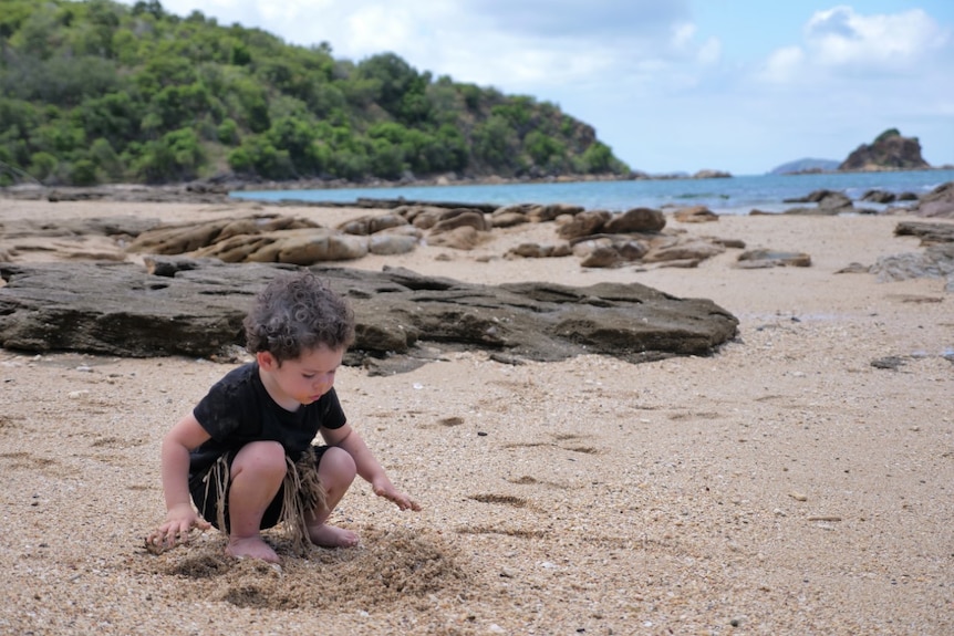 A small boy playing in sand on a beach