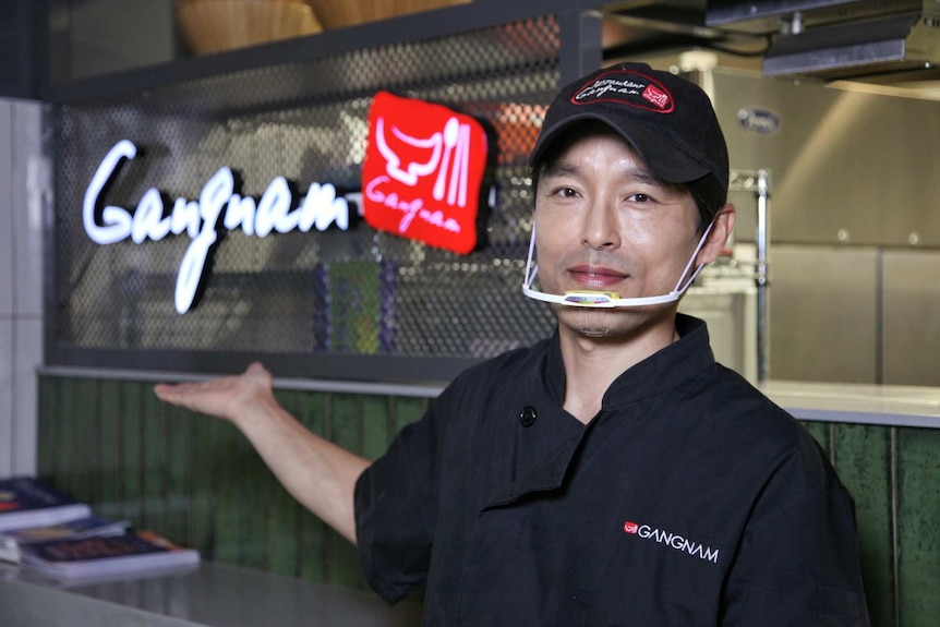 Kuan Sub Lee points to his restaurant sign.