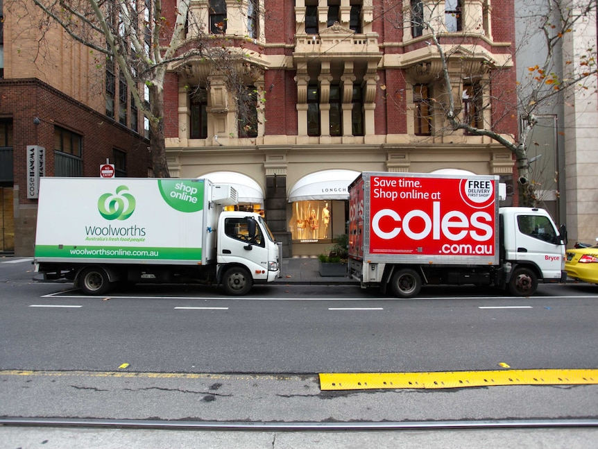 Coles and Woolworths delivery trucks are parked on Collins Street in Melbourne