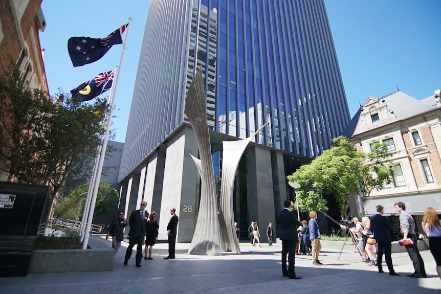 An exterior view from the ground of the high-rise David Malcolm Justice Centre, with a sculpture and people in the foreground.