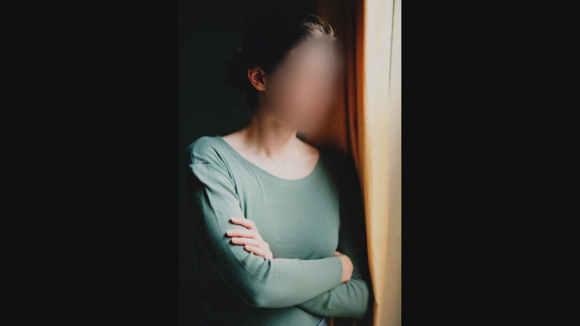 Blurred image of a woman staring out a window.
