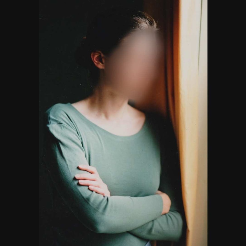 Blurred photo of a woman staring out a window.