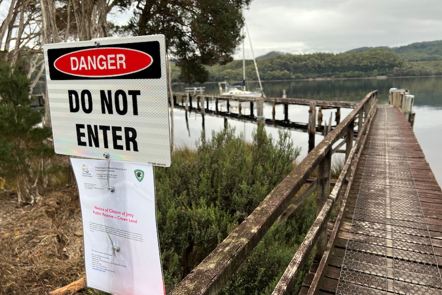 A sign warns of danger in front of an old jetty.