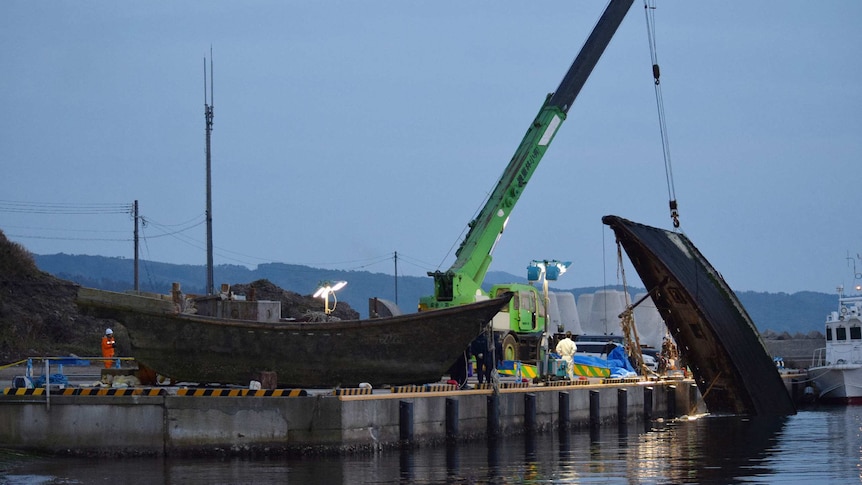 A wooden boat is salvaged at a port in japan.