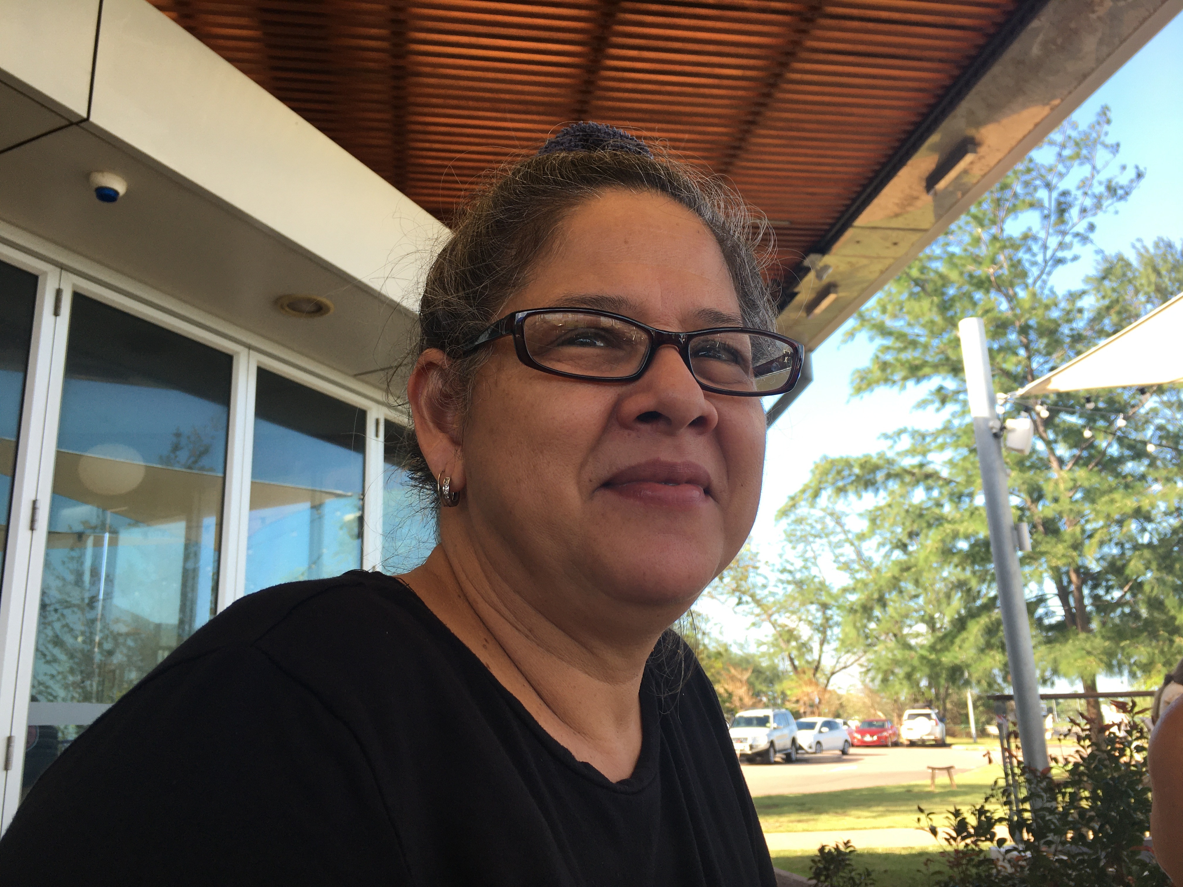 A woman wearing glasses sits at a cafe