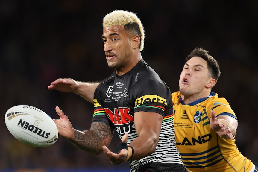 A Penrith NRL player runs with the ball as a Parramatta opponent attempts to make a tackle.