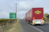 A truck driving next to a sign for a bypass around Penola