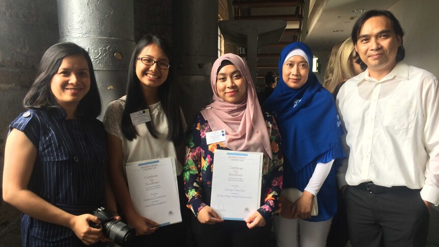 Two Burwood High School students with their certificates and parents.