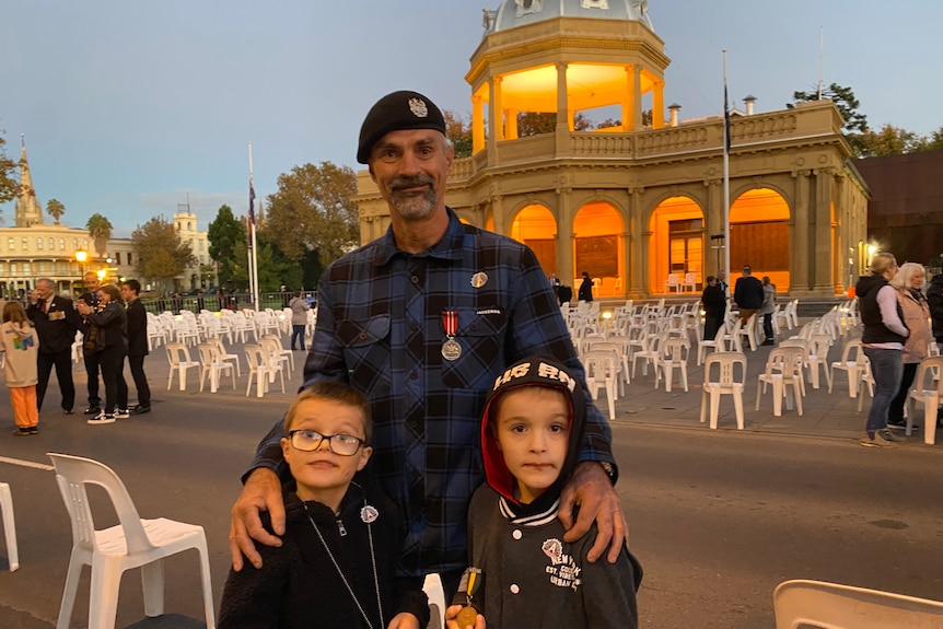 middle aged veteran standing with two young children who are boys at dawn service 
