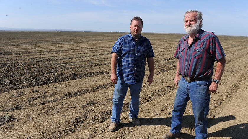 Jim Diedrich (L) and his son Todd stand on some of their farmland which will not be planted this season due to lack of water, in Firebaugh, California.