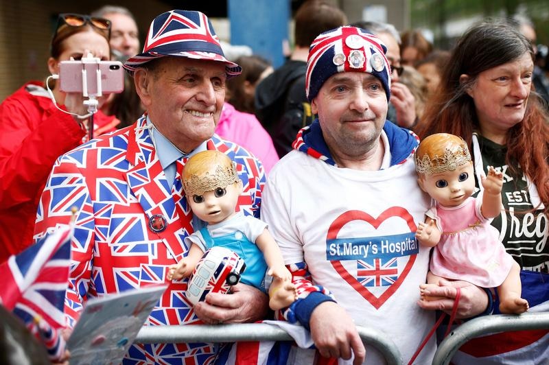 Royals fans, dressed in Union Jack memorabilia, hold baby dolls wearing crowns