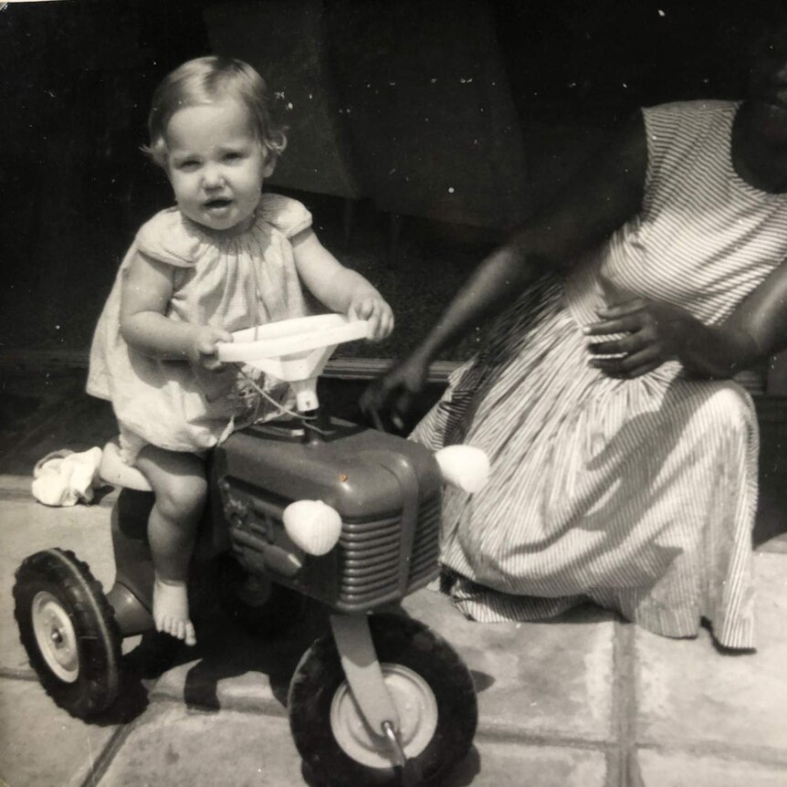Black and white photo of Ferguson as a toddler riding a toy trike.