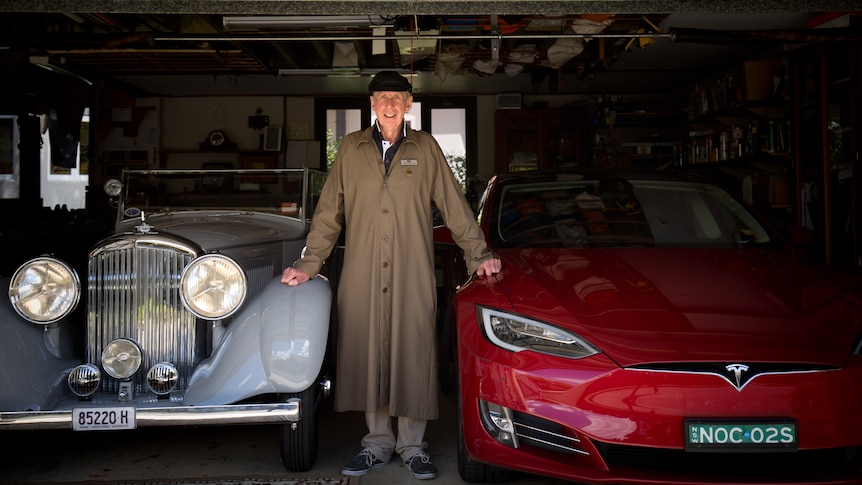 Noel Mcintosh standing in between a1937 Bentley and a modern Tesla.