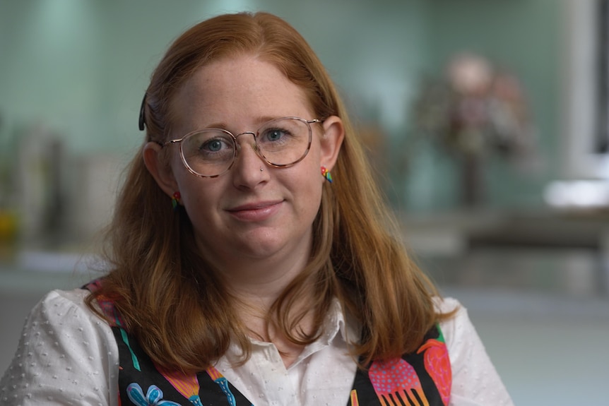 Portrait of a young woman wearing glasses, her shoulder-length hair half up