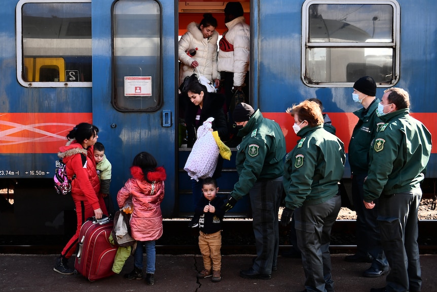 People getting off a train welcomes by authorities.