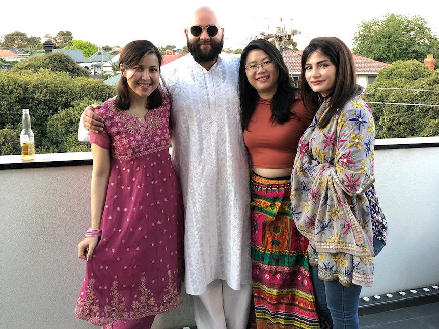 Arjun smiles in a traditional white Indian robe, with non-Indian friends who are also dressed in traditional garments.