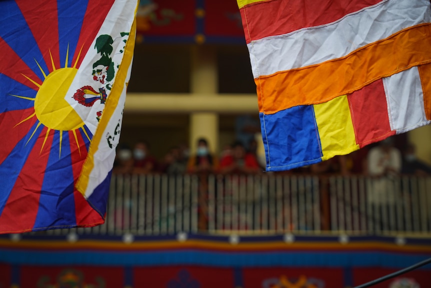 Two flags, one with a yellow sun in the centre and blue and red panels, the other with stripes of red, white, orange