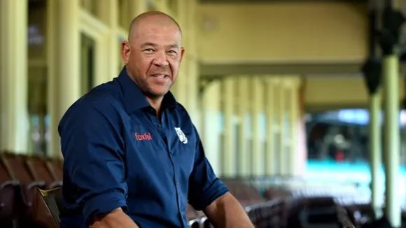 Picture of Andrew Symonds looking at the camera smiling. He is wearing a blue shirt