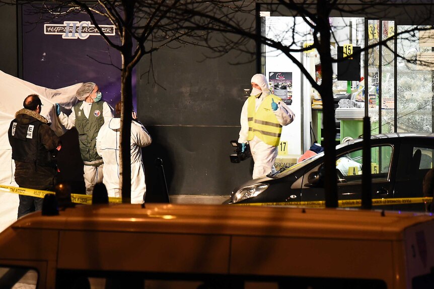 Forensic officers attend the scene of a siege in Paris after the gunman several hostages were killed