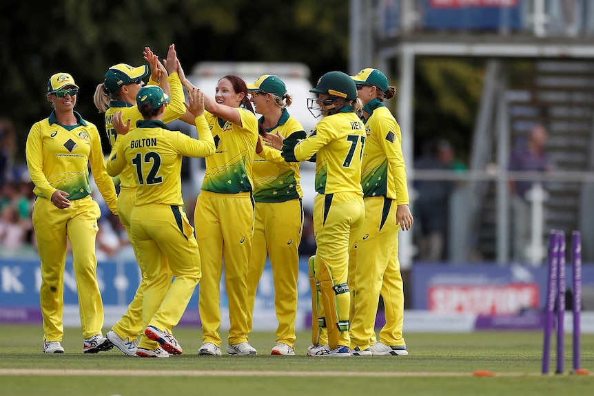 A group of Australian female cricketers celebrate a wicket