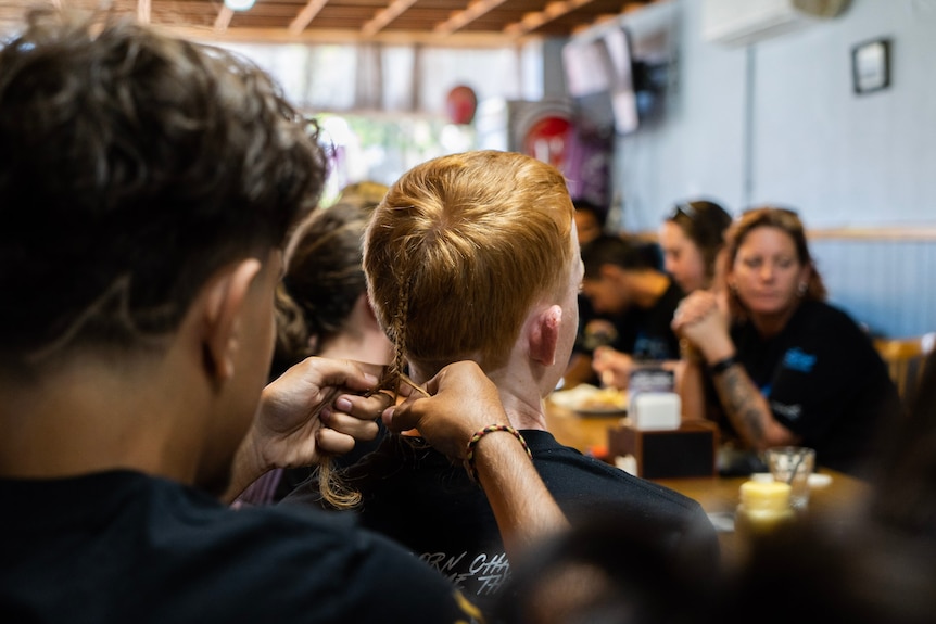 Boy plaits rats tail of friend 