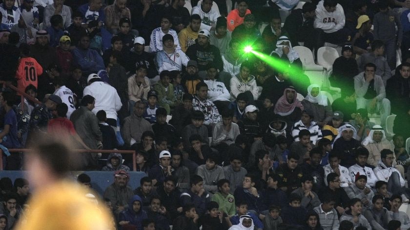 A fan points a laser beam during a match between Kuwait and Australia