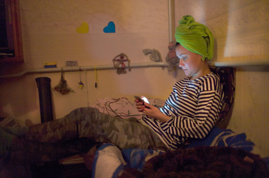 With an anti-tank RPG ready at her bedside, Alla checks her emails in an occupied summer villa after a day on the line.