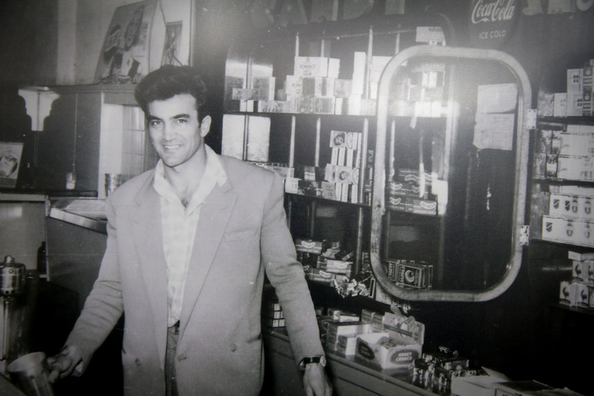 Black and white photograph from the 1950s of a young man standing behind the counter in cafe