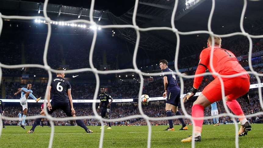 Seen from through goal's net, Raheem Sterling volleys a ball past Everton's goalkeeper.