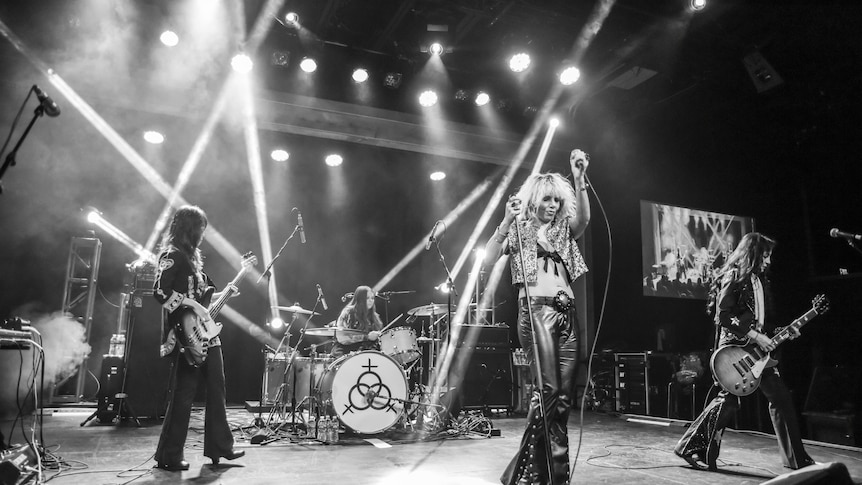 An all-female rock band performs on stage, invoking the iconic looks of Led Zeppelin