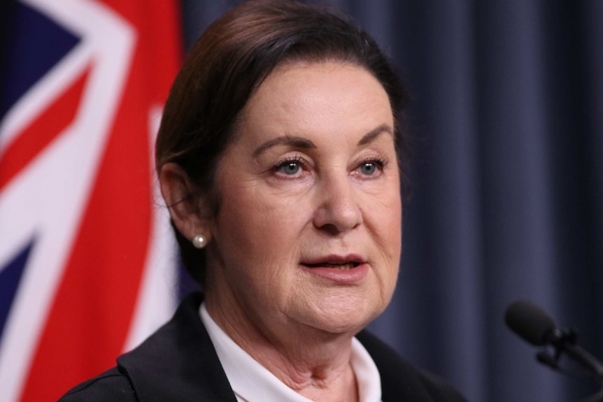 A close up of Jan Shuard in front of an Australian flag.