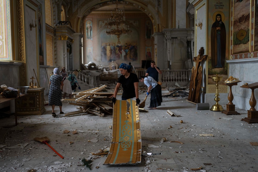 People clean up inside a badly damaged cathedral including picking up rubble
