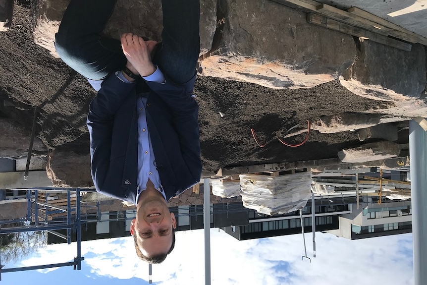 Mayor of Stonnington Steve Stefanopoulos sitting on a rock in front of construction behind him.