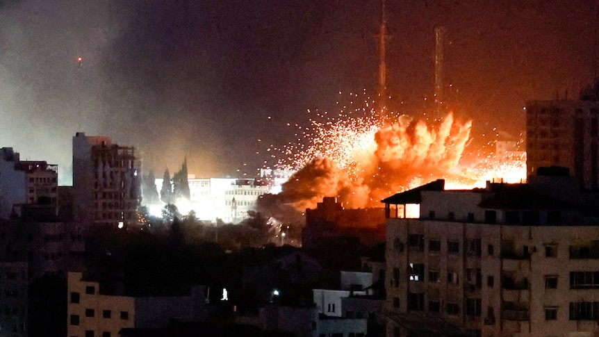 An explosion is seen amongst tightly packed buildings at night time